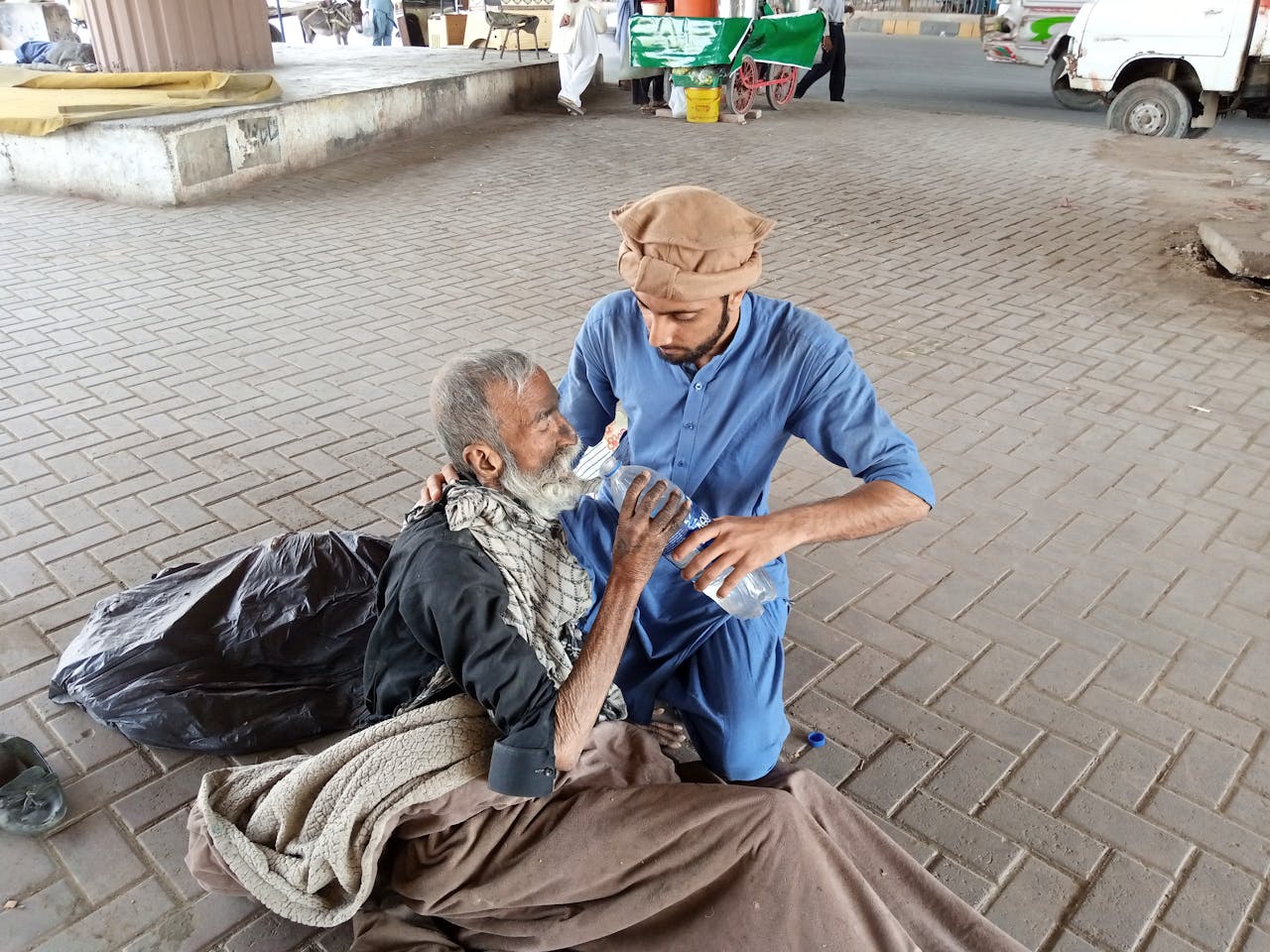 Man In Blue Clothing Feeding An Old Man